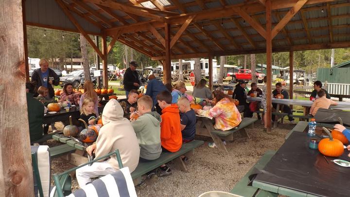 Campers sharing a meal at long tables in the covered pavilion